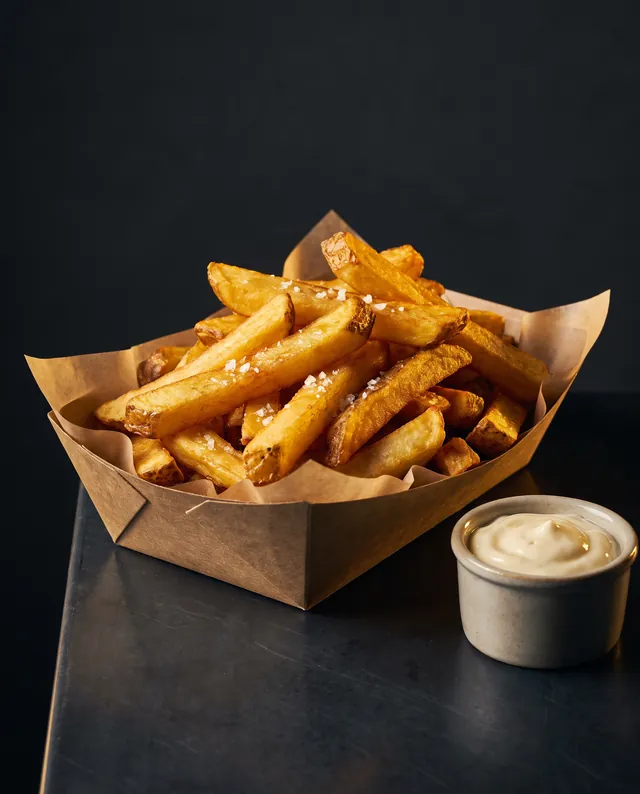 Des frites maison coupées à la main, dorées, avec un ramequin de mayonnaise